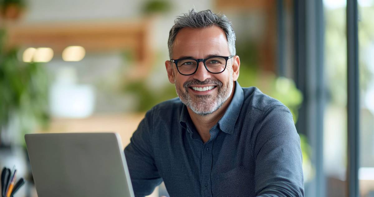 Een glimlachende, volwassen ondernemer met bril en overhemd